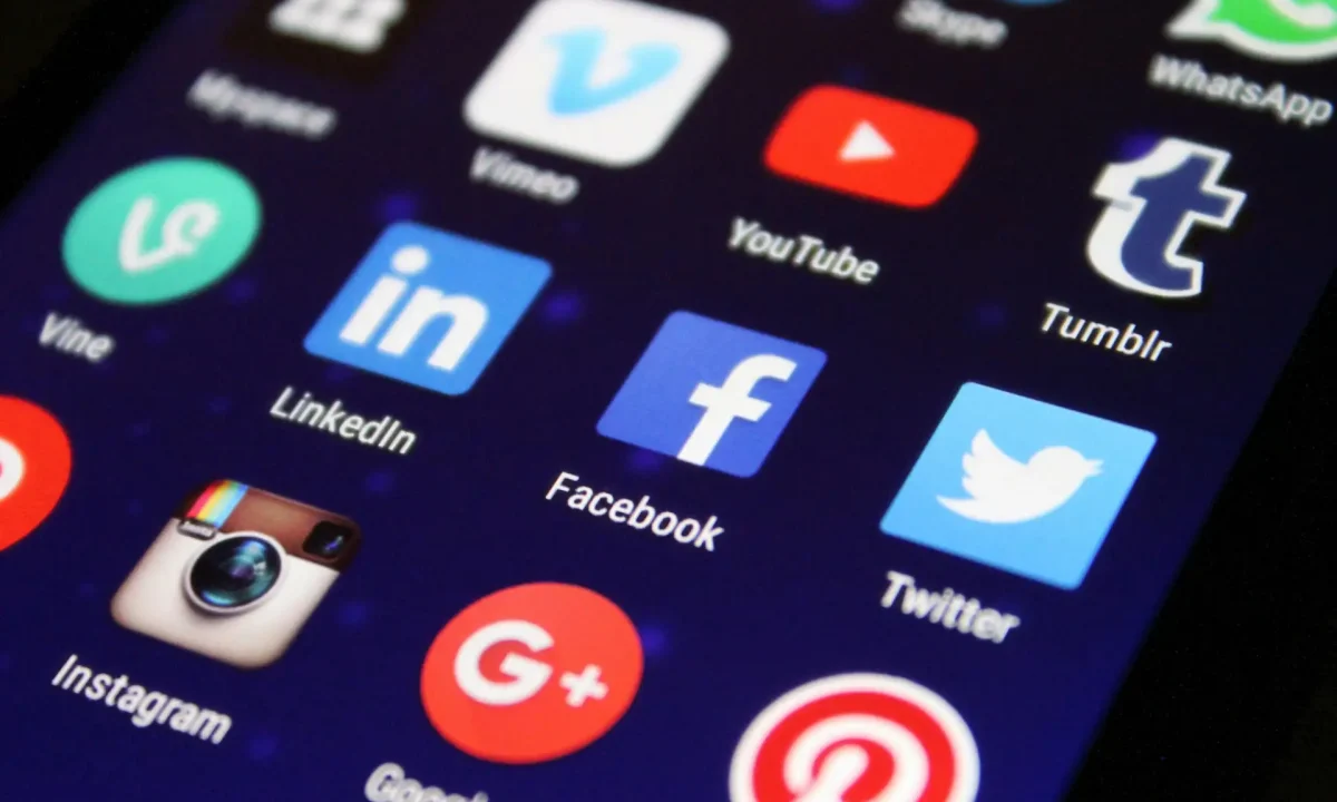 Close-up of a smartphone screen showing various social media app icons such as Facebook and Twitter.